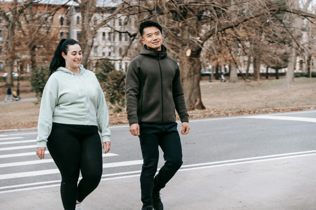 Two friends walking in the park, enjoying a healthy lifestyle and friendship during fall.